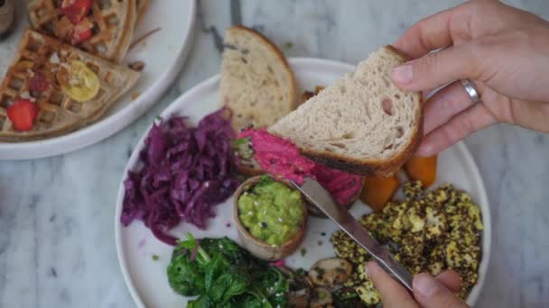 Draufsicht auf Messer, das Rote-Bete-Paste auf einem Toast verteilt. Gesunde vegane Brotaufstriche und andere Vorspeisen auf dem Teller — Stockvideo