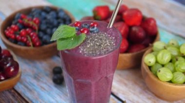 Metal pipetli vejetaryen içeceği. Arkasında böğürtlen dolu tahta kaseler.