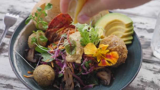 Vue du dessus de la main serrant le citron sur un bol de bouddha végétalien délicieux et sain — Video