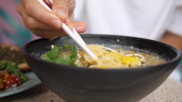 Asiatico street food vegan style.Chopsticks tirando tagliatelle di sana deliziosa zuppa di ramen — Video Stock