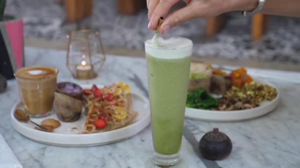 Ruční míchání matcha led latte ve sklenici s kovovým stoke.Healthy Vegan snídaně pro dva. — Stock video