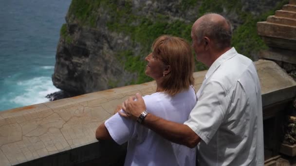 Leven na pensionering. Seniorenpaar op vakantie kijkend naar de oceaan vanaf het terras — Stockvideo