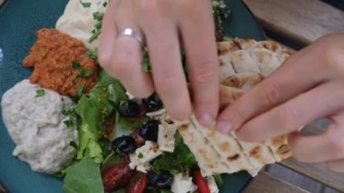 Pide kırılır ve humusa batırılır. Salata, sos ve pide ile ezme tabağı. Sağlıklı organik Orta Doğu mutfağı. 