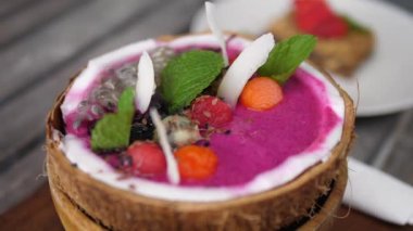 Tatillerde kahvaltı. Hindistan cevizi kasesinde müsli ve bir bardak kahveyle servis edilen ejderha meyveli smoothie 'nin detaylı görüntüsü.. 