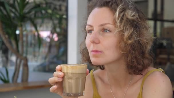 Menina caucasiana toma um gole de seu café latte vegan com grande apreço, olhos fechados, sentindo o sabor. Início perfeito de um dia — Vídeo de Stock