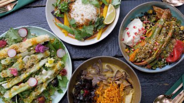 Siyah ahşap masaya iki tabak sağlıklı organik vejetaryen yemeği servis ediyorum.