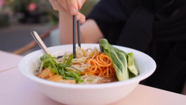 Caucasian girl eating noodles from healthy vegan ramen soup. Asian street food — Stock Video