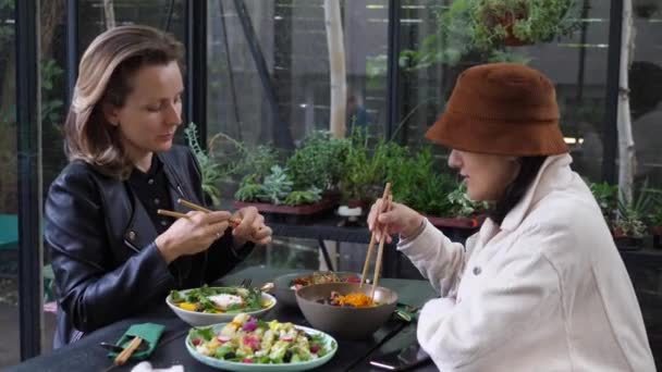Két barátnő beszélgetett az egészséges vegán ebédjükről keleti stílusban. Élvezi ízletes egészséges ételek és minőségi időt a barátaival — Stock videók
