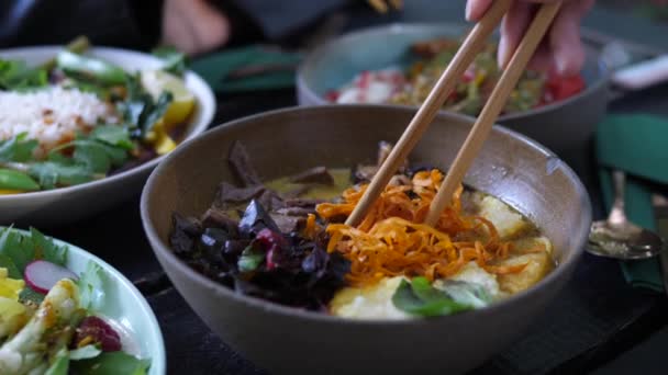 Κοντινό πλάνο των chopsticks ανάμειξη συστατικών σε υγιή vegan σούπα. Υγιεινή ασιατική έννοια των τροφίμων δρόμο — Αρχείο Βίντεο