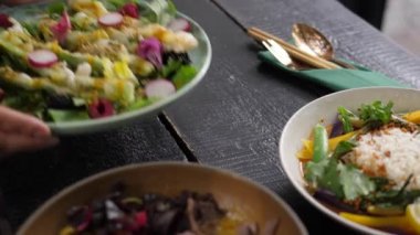 İki kişi salata vejetaryen yemeklerini çorbaların yanına koyuyor. Sağlıklı bir şekilde yemek yemek. 