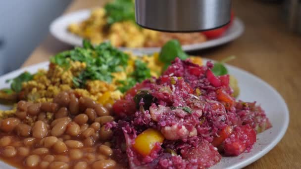 Nahaufnahme von Würze mit Mahlwerk veganes Frühstück aus Tofu-Omelett, Bohnen und Salat — Stockvideo
