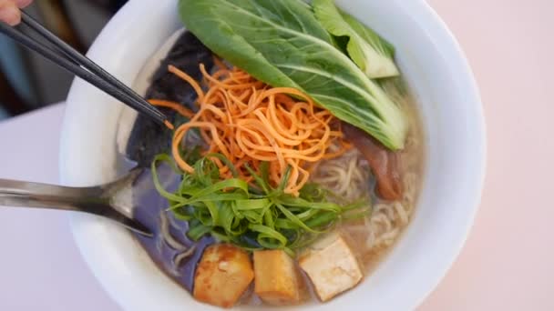 Ramen çorbasını yemek çubuklarıyla karıştıran el manzarası. Sağlıklı Asya mutfağı — Stok video