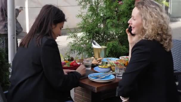 ผู้จัดการหญิงสองคนที่ร่าเริงพูดคุยเรื่องงานของพวกเขาในช่วงอาหารกลางวันธุรกิจ คนงานที่มีความสุขและมีประสิทธิผล — วีดีโอสต็อก