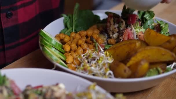 Ruční plnění misky s omáčkou do talíře se salátem. Rustikální styl veganské domácí Buddha mísa — Stock video