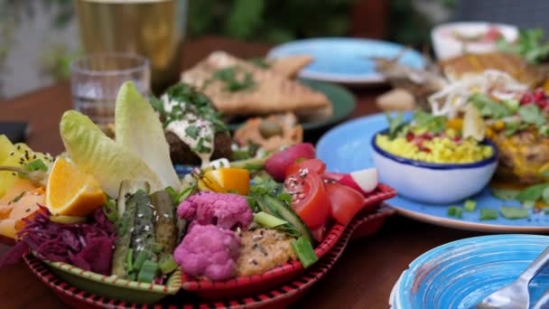 Veganistisch tuinfeest eten. Midden-Oosten meze van hummus, falafel baba ganoush, tabbouleh en augurken. Thaise kokosnoot ananas curry. — Stockvideo