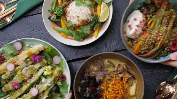 Serveren van twee borden met gezonde biologische veganistische maaltijden aan de zwarte houten tafel — Stockvideo