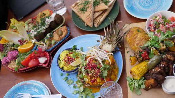 Draufsicht auf verschiedene gesunde vegane Optionen aus der globalen Küche. Nahöstliches Meze, indisches Curry, amerikanisches Soja meets Barbecue — Stockvideo