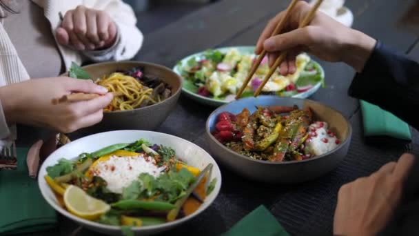 Pausa pranzo al ristorante di cucina orientale. Pasti serviti in ciotole colorate su tavolo di legno nero. — Video Stock