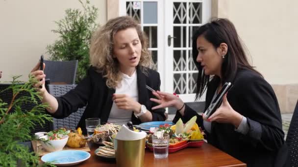 หญิงธุรกิจสองคนมีวิดีโอโทรหาเพื่อนร่วมงานในช่วงมื้อเที่ยงธุรกิจ การดําเนินธุรกิจที่ประสบความสําเร็จจากระยะไกล — วีดีโอสต็อก