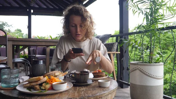 Staying connected virtually. Young Caucasian woman shares her breakfast on a video call and describes all the dishes