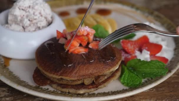 Händer styckning stack pannkakor med gaffel och kniv. Friska växtbaserade frukost — Stockvideo