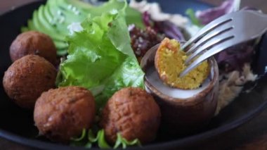 Kremalı vejetaryen sosuna falafel batırmaya yakın. Sağlıklı organik bitki tabanlı