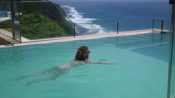 Tropischer Urlaub. Blondes Schwimmen und im Infinity-Pool. — Stockvideo