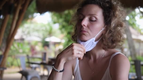 Yalnız sarışın kız, sahil barında Meksika sokak yemeklerinin tadını çıkarmak için maskesini çıkarıyor. Covid-19 salgını sırasında tek başına seyahat etmek — Stok video