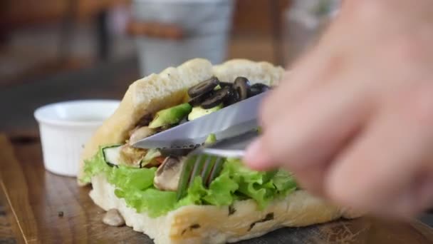 Händer skära en växtbaserad smörgås full av grönsaker wirth bestick — Stockvideo