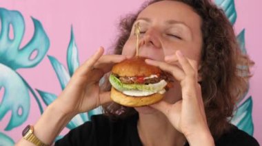 Çok aç genç bir kadın vejetaryen hamburgerini büyük bir zevkle yer.