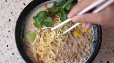 Yemek çubuklarının en üstteki görüntüsü kamerada bitki bazlı vejetaryen ramen çorbasının eriştelerini gösteriyor. Vegan Asya mutfağı