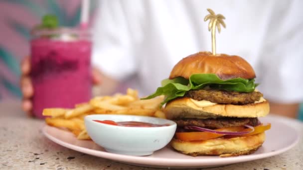 Növényi alapú utcai kaja ebédre. Burger sültkrumplival, bogyós turmix — Stock videók