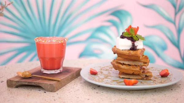 Healthy balanced vegan dessert of waffles and plant based milkshake. The Pink wall on the back