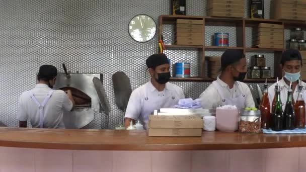 Open keuken in een pizzeria. Een rij chef-koks met maskers aan het praten. Bali-December-2020 — Stockvideo