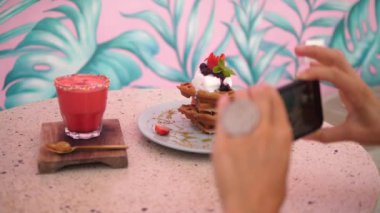 İnsan eli Belçika 'nın vejetaryen waffle' larının ve bitki bazlı milkshake 'lerin fotoğrafını çekiyor.
