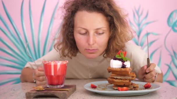 Retrato de una mujer caucásica hambrienta mirando los gofres veganos y batido a base de plantas anticipando su almuerzo — Vídeos de Stock