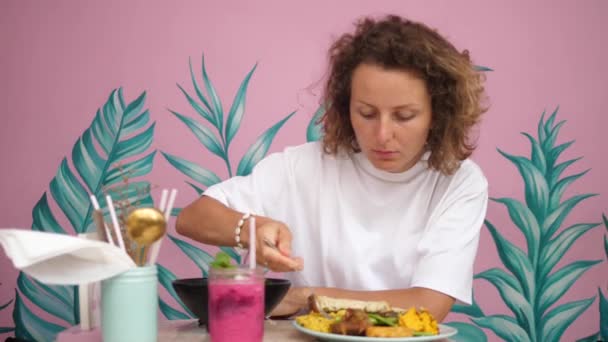Νέα ξανθιά γυναίκα τρώει υγιεινά νόστιμα vegan πρωινό της. Απολαμβάνοντας σόλο ταξίδι — Αρχείο Βίντεο
