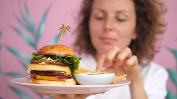 Mladá běloška si vychutnává oběd dvoupatrového veganského burgeru a hranolek — Stock video