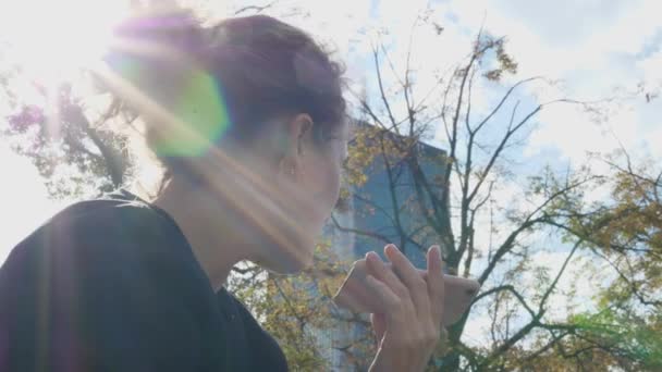 Kvinna inspelning röst meddelande på smartphone på en solig dag i parken — Stockvideo