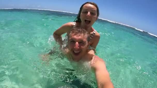 Romantic holidays concept. Young couple playing in an ocean looking to the camera — Stock Video