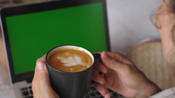 Malam yang nyaman. Seorang wanita menikmati acara favoritnya menonton pada komputer dan secangkir tanaman latte berbasis — Stok Video