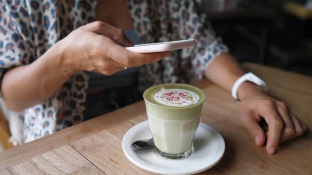 Blogger taking a picture of green tea matcha latte decorated with flowers. Healthy organic plant based drinks — Vídeo de stock