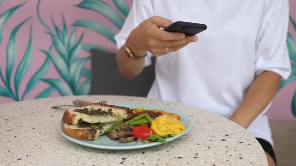 Food blogging. Mani in possesso di smartphone alla ricerca di un angolo perfetto per scattare una foto di sana colazione vegana biologica. — Video Stock