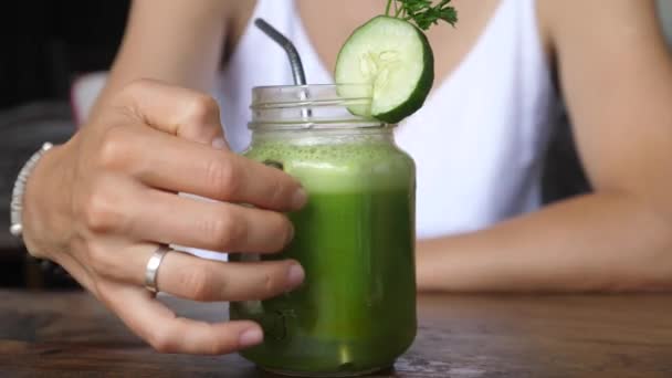 Femme cueillette à la main un pot de jus pressé à froid vert biologique avec de la paille métallique durable — Video