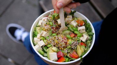 Hızlı yemek için sağlıklı yemek teslimatı. Yeşil sebze salatasıyla lahanayı, tofuyu, mikroyeşillikleri geri dönüşümlü kağıt pakette karıştırın.
