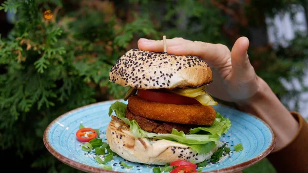 Bezmięsne alternatywy tradycyjnej żywności. Kobieta ręka naciskając w dół duży wegetariański burger, aby móc ugryźć — Zdjęcie stockowe