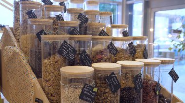 Granola, fındık, tohum, tahıl, uzun cam kavanozlardaki kuru meyveler satılık. Çevreye duyarlı tüketiciler için sürdürülebilir çözüm olarak paketsiz depo 