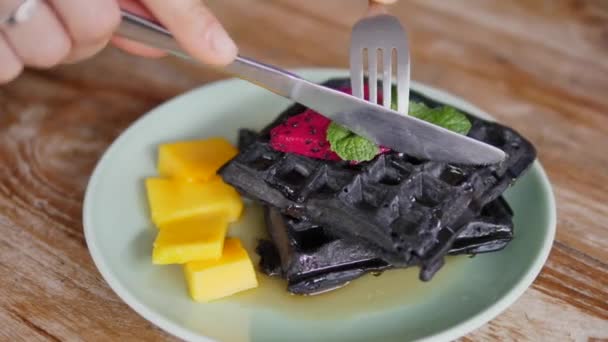 Верхній вигляд рукопашних чорних бельгійських веганських вафлів зі срібною обрізкою. Десерт подається на дерев "яному столі. — стокове відео