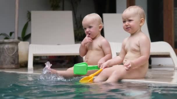 Kaukasische Zwillingskleinkinder spielen mit Wasser in ihrem Schwimmbad. Glückliche Kindheit — Stockvideo