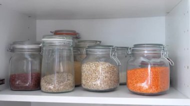Bitki temelli diyet ve sağlıklı yiyecekler. El, organik fasulye ve tahıllarla dolu bir kavanoz tahıl topluyor. 